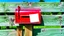 Placeholder: an old wooden fence, , a red old mailbox on the fence, a big note stuck on the mailbox