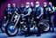 Placeholder: a very hard and tuff motorcycle bald gang, not old, posing with their Harley Davidsson bikes, some of them holding guns and shotguns, a logo sign with Falköpings HD Club, "Fearless sinners" Skulls and bones, skeletons