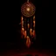 Placeholder: a dreamcatcher made of light, glowing internal light, natural red/brown tones, brown dirt ground long bottom, dark background
