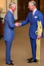 Placeholder: The Prince of Wales in traditional dress shakes hands with a young guest dressed in a blue suit, drawing room of St James's Palace, during a reception