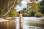 Placeholder: beautiful girl in pretty dress walking in water toward camera in trees next to wavy river with clear water and nice sands in floor.camera capture from her full body front