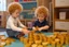 Placeholder: a curly-haired blond boy counts money and stacks gold coins in a modern nursery, in sunshine