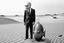 Placeholder: imitating analog photography in black and white, man with a fish tank instead of a head, three-piece suit, in a desert, realism, white and black photographic, analog photography grain texture