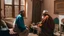 Placeholder: Two fifty-year-old people in traditional Moroccan clothing are discussing in the room of a Moroccan house, with only their backs visible