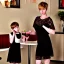 Placeholder: Russian guy young mommy boyish boylike short man's haircut boyish features in black girlish lacy cocktail dress as mother in restaurant