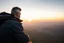 Placeholder: a brawny man with grey hair views sunset from a cliff