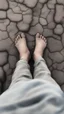 Placeholder: A side view of an old cracked feet with bad toes without shoes on a cracked dry ground in grey foggy ground side view