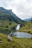 Placeholder: country side with a small lake and a pretty height fall that comes out of a nearby mountain rocks and falls to calm lake