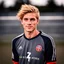 Placeholder: 85mm DSLR color photography of a very detailed headshot fitting all of head and hair in frame. 22-year-old Germen soccer player, with blonde hair color and no facial hair and with a small smile, grey background