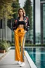 Placeholder: fullbody shot of young-beautiful-girl-with-a-perfect-face-with-make-up-wearing- sport pants and jacket standingnext to a big Square with a flowers and small round pool with clean water in center , modern city scape environment .