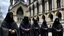 Placeholder: hooded monks in black robes in front of cathedral