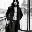 Placeholder: A young Asian man with long hair and a black trench coat waiting for a woman at a train station in Paris