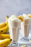 Placeholder: A detailed close-up of banana milkshakes, captured in a vibrant and appetizing food photograph. The milkshakes are presented in tall glasses, topped with whipped cream and garnished with fresh banana slices. The background is blurred to focus on the milkshakes, with soft, natural lighting that highlights the creamy texture and burst of flavor. The image evokes a sense of indulgence and delight, making the viewer crave a sip.