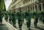 Placeholder: Soldiers marching in formation; military parade; marching along a street; green uniforms; medals and insignia; Rifles in their hands;