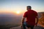 Placeholder: a brawny man with grey hair views sunset from a cliff