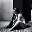 Placeholder: [art by helmut newton] In humble submission, she kneels, a canvas of desire, Offering her back to the whisper of anticipation's fire. On hands and knees, she waits, a portrait of allure, Her essence bared, ready for the touch so pure. In the tender twilight, she bows, a vision of grace, Awaiting the sweet sting of passion's embrace