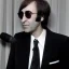 Placeholder: Tom Snyder in a suit leaning forward to talk to John Lennon, 1980s