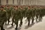 Placeholder: caucasian soldiers; marching in formation; away from camera; military parade; tight formation; shoulder to shoulder; marching along a street; green uniforms; medals and insignia; weapons in hands;