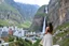 Placeholder: A modern city at the foot of the mountain. The entrance valley with a waterfall from a high rock. A beautiful lady in a top and midi skirt.