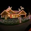 Placeholder: photograph taken by a gopro camera of a suburban house and landscaping and fence with an insanely detailed Christmas light display lit up at night. Christmas lights on everything, Santa's sleigh and reindeer on roof all lit up with individual christmas lights, christmas light on everything to an unbelievable degree