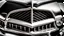 Placeholder: Photograph of a the front grill of a gorgeous, expensive, oldschool black muscle car with a big, black front grill, realistic, stylish, taken up close, symmetrical