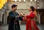 Placeholder: A photorealistic image of a young Azerbaijani couple in their twenties performing a traditional dance. They wear authentic traditional clothing - the man in a black chokha with silver details, the woman in a vibrant red dress with gold embroidery. They are dancing joyfully in a historic courtyard at golden hour, looking at each other with happy expressions. The image captures the dynamic movement of their dance and the beauty of Azerbaijani culture.
