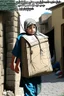 Placeholder: A Palestinian child carries on his shoulders a large bag with windows and doors