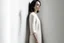 Placeholder: Woman wearing a wool dress, leaning against a white wall, fashion photography, real photography,16K