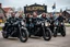 Placeholder: a very hard and tuff motorcycle young gang with Keltic hair , not old, posing with their Harley Davidsson bikes, some of them holding guns and shotguns, a logo sign with "FALKÖPING HD", "FEARLESS SINNERS" Skulls and bones, skeletons and fire, Swedish town Falköping in background, Swedish flags on bikes, Simon Stålenhag style