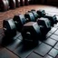 Placeholder: Hexagon dumbbells pair of two, each 12.5KG. Inside a gym on the black rubber tile floor. Bird perspective on the dumbbells laying on the floor.