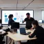 Placeholder: Coders collaborate, in an office environment, huddled at large screens, and writing new code together, photography