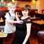 Placeholder: Russian guy young mommy boyish boylike short man's haircut boyish features in black girlish lacy cocktail dress as mother in restaurant