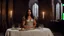 Placeholder: [Conan The Barbarian (1982)] In the dining room of the large castle, she sits alone in a linen dress at the grand table. The flickering candlelight casts dancing shadows across the walls. Her eyes are drawn to a majestic statue mounted on the wall, depicting a woman clad in armor, strikingly similar to herself. The intricately carved features of the armored woman seem to gaze back at her, as if urging her to embrace her destiny.