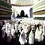 Placeholder: The scene in Mecca: People wearing white Ihram clothes, men without head coverings, women with veils, circumambulating around the Kaaba, and above them are transparent white spirits of children, men, and women with wings revolving around the Kaaba.