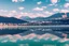 Placeholder: Sunny day, modern city, lake, lake reflections, people, mountains