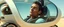 Placeholder: close up on weird out expression of guy suspended in straps inside laid back futuristic sci-fi glass human form car pillar on wheels, and a tracked wheel in the middle of the car, his face is flattened by the window