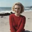 Placeholder: Childish Norma jeane baker in a red woollen sweater, on the beach, in the sun