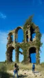 Placeholder: ruined buildings with people and blue sky and foliage