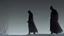 Placeholder: Black robed, hooded monks in the field