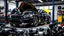 Placeholder: A car repair shop where two people in work clothes are repairing a black and yellow BMW M6 series with an eye-catching theme in a sophisticated and special repair shop where a collection of car engine parts is arranged on the floor at the bottom of the image.