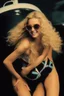 Placeholder: extremely tiny, thin, beautiful Sheena Greane with long, wavy curly blonde hair, wearing a wearing swimming gear, smiling a happy smile, extremely giant, oversized, humongous orbs, pitch black background, professional quality studio 35mm 8x10 uhd photograph, sunglasses