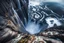 Placeholder: at the base of the rocky mountain peninsula, a great whirlpool waterfalls into deeper unknown depths