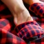 Placeholder: Red plaid slippers laying on a bearskin rug by log cabin woodstove