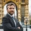 Placeholder: an man standing in front of big ben looking at camera,closeup