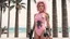 Placeholder: A modern Barbarella warrior with a machine gun covered by tattoos, 24-years-old wearing a pink one-piece swimsuit [vintage style noisy scratches glitches, Shot the texture and then rewound the film and double exposed from a 1970 B series movie] she stands in the marble palace of a modern dictator the beach and palm trees by the windows