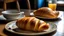 Placeholder: a croissant/ gipfeli which is a pastry from france on a plate. the plate is on a table