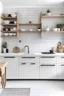 Placeholder: white kitchen with black handles , with white work surface, hexagon white marble backsplash, white marble floor and 1 wooden shelf with small plant and wicker baskets