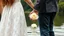 Placeholder: close up Back view couple holding hands close a lake, a white rose swims on the water, in the blur background a lake, some green trees, ultra detailed, sharp focus, perfect anatomy, perfect hands with fingers, perfect photo