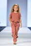 Placeholder: 2 years old beautiful baby blue eyes girl fashion model in loose pants and loose top with blonde curvy wavy hair ,cat walks in runway,catwalk and pose at end with cute