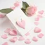 Placeholder: A photo of a white card, 5.5 by 4.25 inches. The card is vertically positioned on a beautiful light pink surface, positioned between pink rose petals and litte golden hearts.